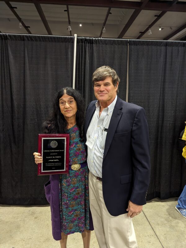 Nancy White holding her Lifetime Achievement Award next to T.R. Kidder